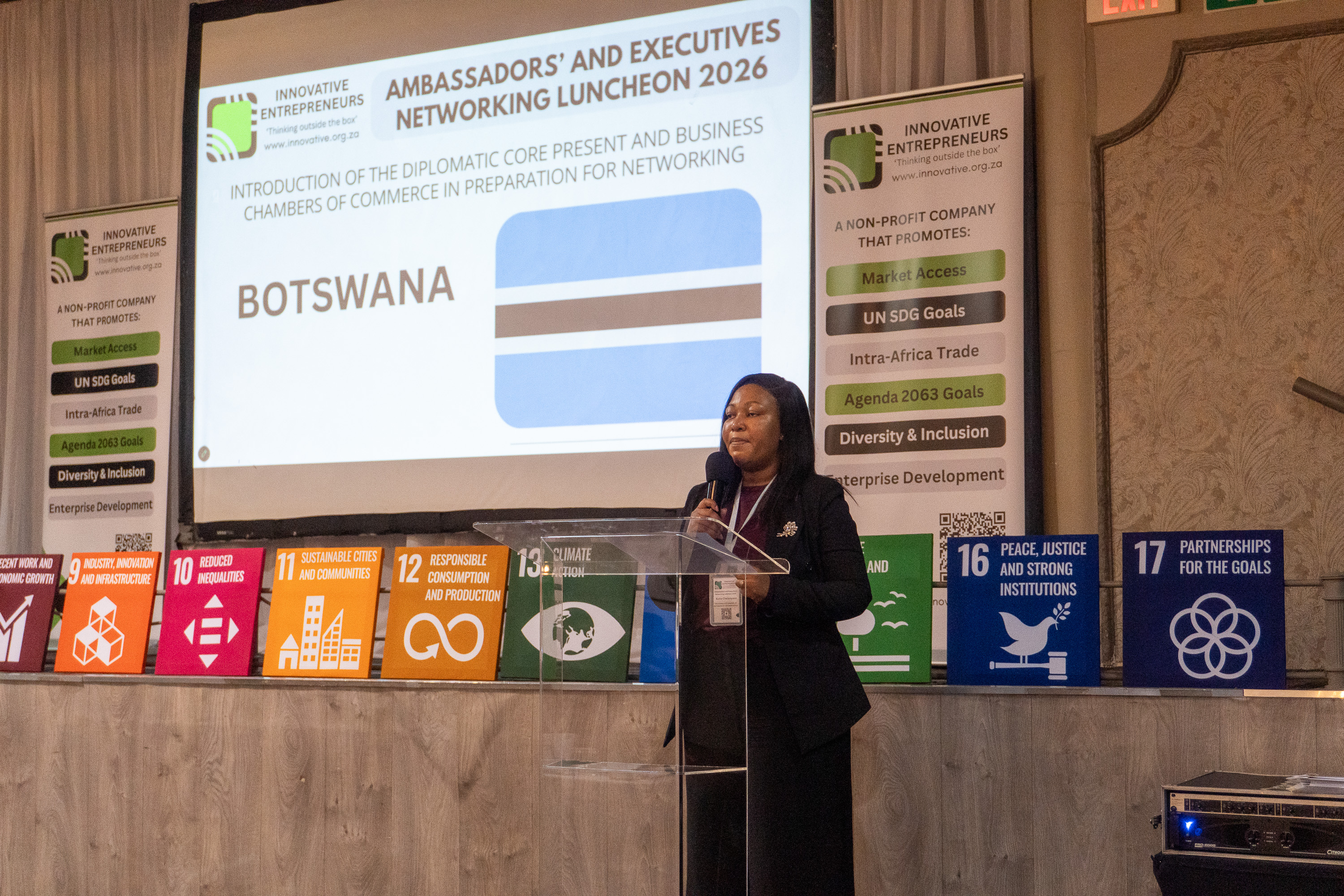 A Botswana diplomatic representative addresses AENL 2026 with the Botswana flag projected behind