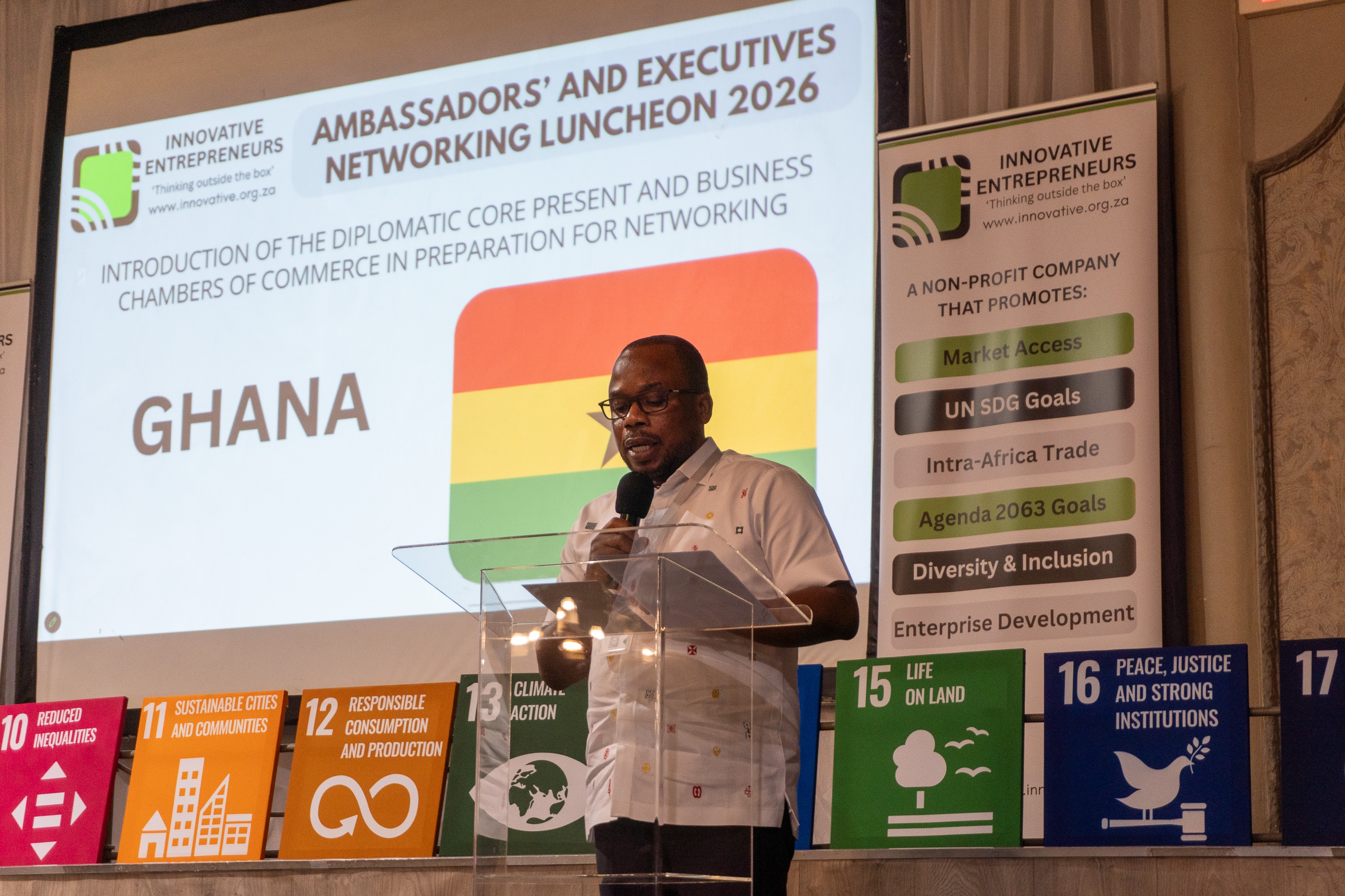 A Ghanaian diplomatic representative addresses AENL 2026 with the Ghana flag projected behind