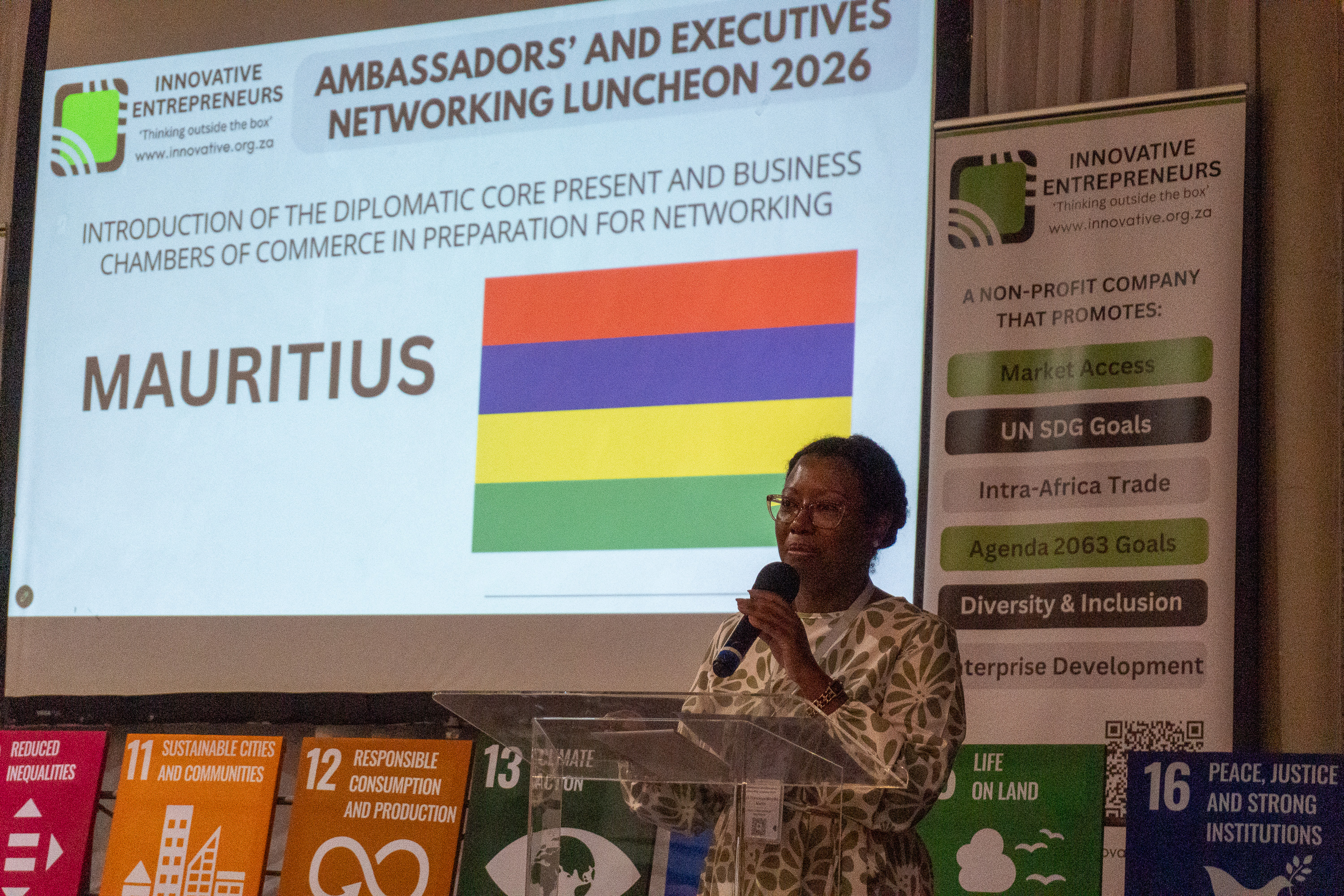A Mauritius diplomatic representative speaks at AENL 2026 with the Mauritius flag projected behind