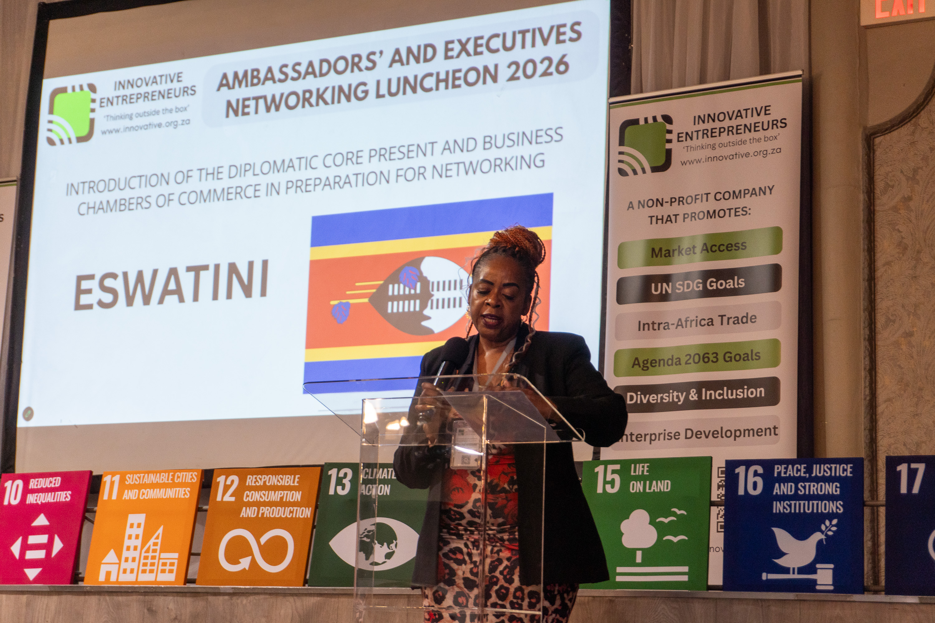 An Eswatini diplomatic representative speaks at AENL 2026 with the Eswatini flag projected behind