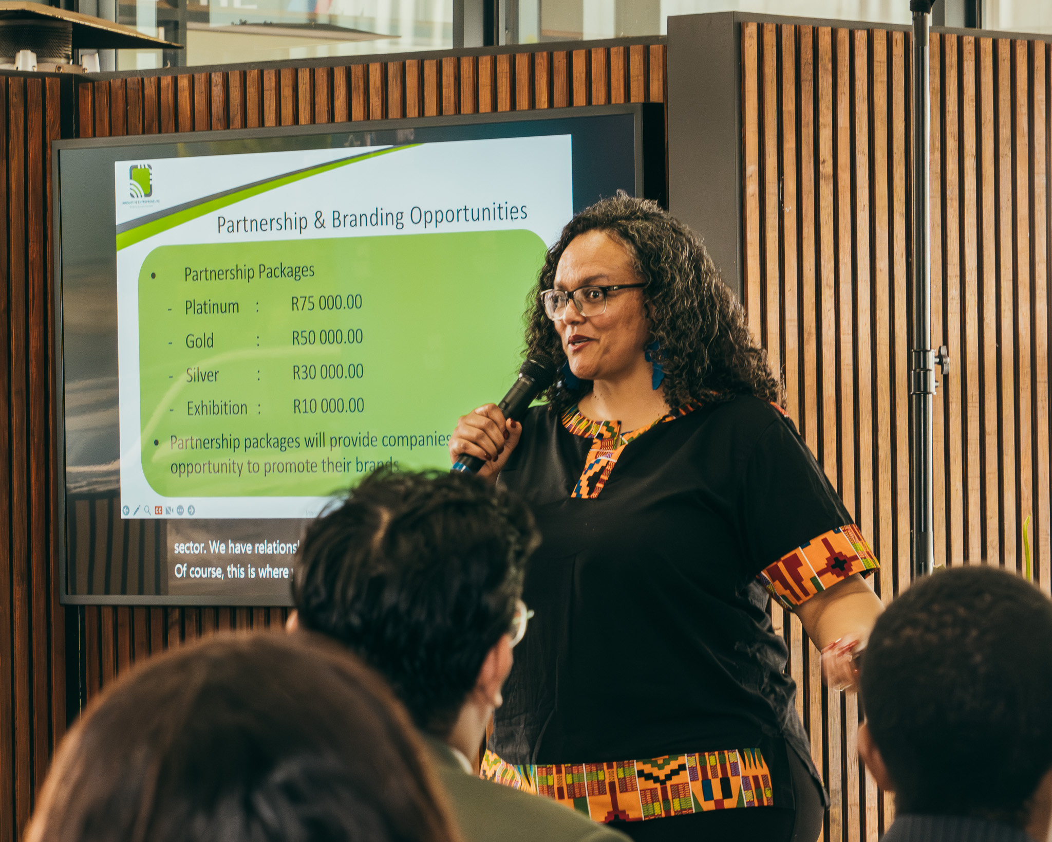 Three diverse individuals promoting inclusive entrepreneurship in South Africa. A young Black woman in a wheelchair holds a sign for UN SDG 8: Decent Work and Economic Growth, alongside two colleagues holding signs for Good Health and Quality Education.